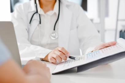 Médica revisando anotações em um prontuário enquanto conversa com paciente sobre planejamento personalizado de tratamento.